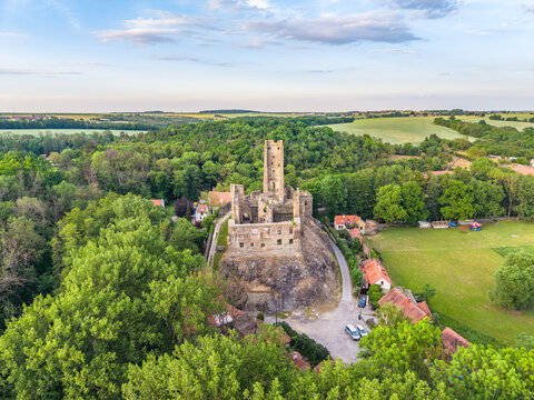 Aerial view of the historic ruins of Okor Castle surrounded by lush green forests and rolling fields in the countryside of Okor, Stredocesky kraj, Czechia.