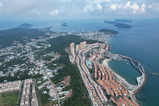 Aerial view of the colorful Mediterranean-style Sunset Town with vibrant buildings, sandy beach, and modern architecture along the coastline in Phu Quoc, Kien Giang, Vietnam.