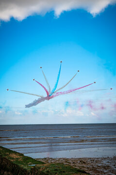 London, England, United Kingdom - 07 July 2026: View of the Red Arrows aerobatic team performing a formation flight with smoke trails over a coastal beach.