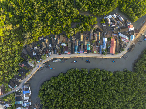 Aerial view of Hin Rom Pier surrounded by a coastal village, small boats moored along the canal, and lush mangrove forests in Tambon Khlong Khian, Chang Wat Phang-nga, Thailand.