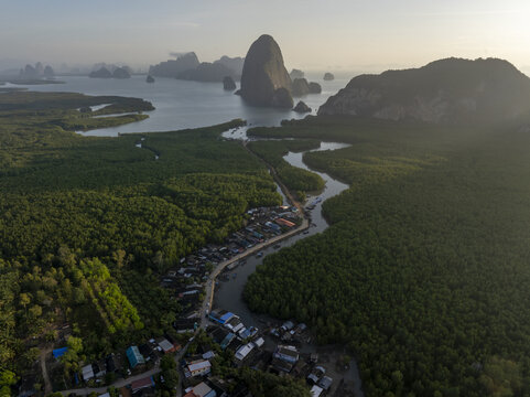 Aerial view of Hin Rom Pier surrounded by lush mangrove forests and limestone karst formations along the coast in Tambon Khlong Khian, Chang Wat Phang-nga, Thailand.