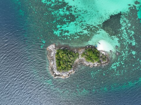 Aerial view of Ko Hin Ngam Noi surrounded by turquoise coral reefs and clear blue sea in Ko Tarutao, Satun, Thailand.