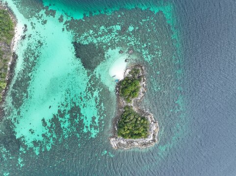 Aerial view of Ko Hin Ngam Noi surrounded by turquoise coral reefs and deep blue Andaman Sea waters in Ko Tarutao, Satun, Thailand.