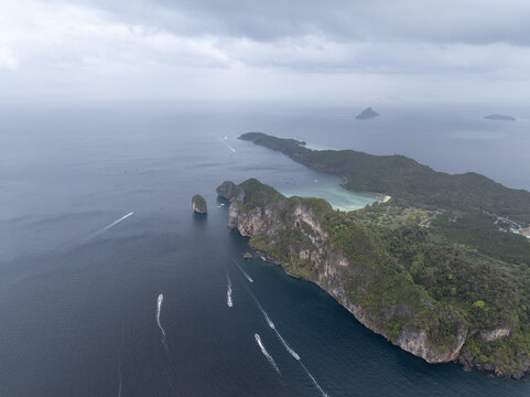 Aerial view of Loh Lana Bay featuring dramatic limestone cliffs, turquoise waters, and boats leaving wakes in the Andaman Sea, Tambon Ao Nang, Chang Wat Krabi, Thailand.
