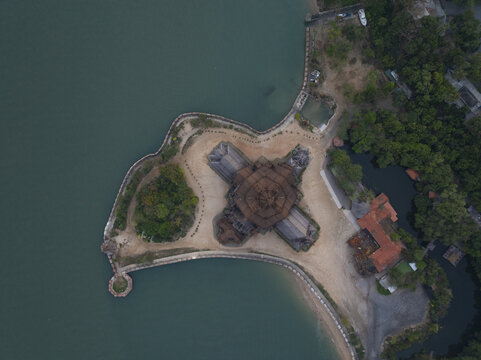 Aerial view of The Sanctuary of Truth Museum, a wooden temple structure surrounded by lush greenery and coastal waters in Muang Pattaya, Chang Wat Chon Buri, Thailand.