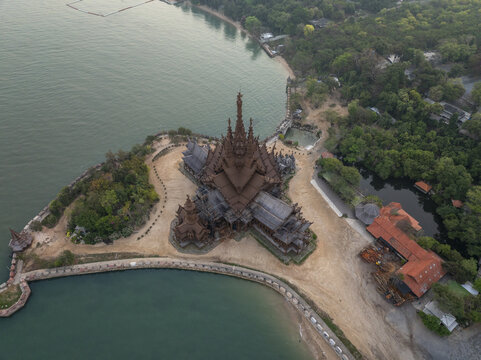 Aerial view of The Sanctuary of Truth Museum, an intricate wooden temple on a coastal headland surrounded by lush greenery and the sea in Muang Pattaya, Chang Wat Chon Buri, Thailand.