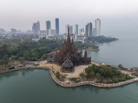 Aerial view of The Sanctuary of Truth Museum, an intricate wooden temple on the coast, with the modern Pattaya skyline Muang Pattaya, Chang Wat Chon Buri, Thailand.