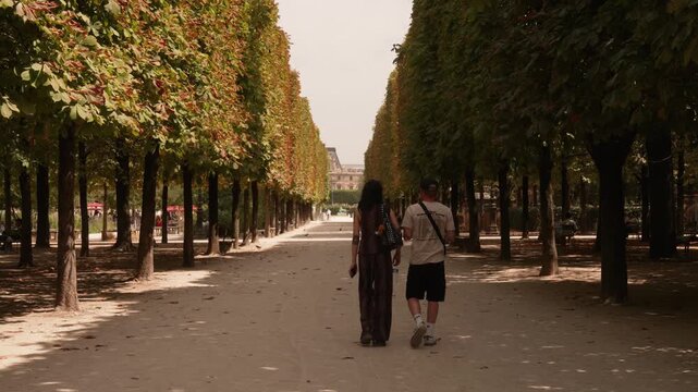 Gravel avenue under clipped trees in the Tuileries Garden Paris with couple walking