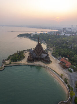 Aerial view of The Sanctuary of Truth Museum, an intricate wooden structure on the coast surrounded by lush greenery and calm sea in Muang Pattaya, Chang Wat Chon Buri, Thailand.