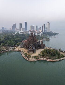 Aerial view of The Sanctuary of Truth Museum, an intricate wooden temple on the coast with lush trees, set against the Pattaya skyline, Muang Pattaya, Chang Wat Chon Buri, Thailand.