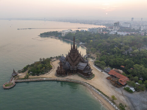 Aerial view of The Sanctuary of Truth Museum, an intricate wooden structure on the coast surrounded by lush greenery and calm waters in Muang Pattaya, Chang Wat Chon Buri, Thailand.