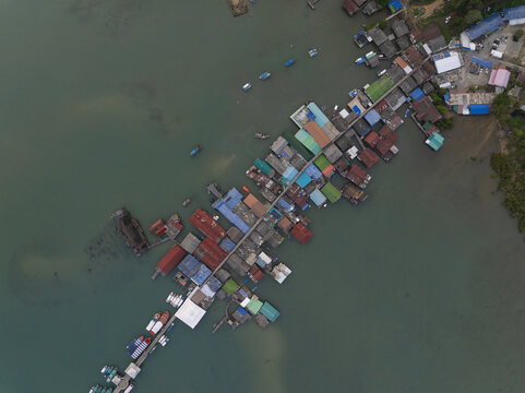 Aerial view of Bang Bao Pier with its stilt houses and fishing boats extending into the calm bay in Koh Chang, Trat, Thailand.