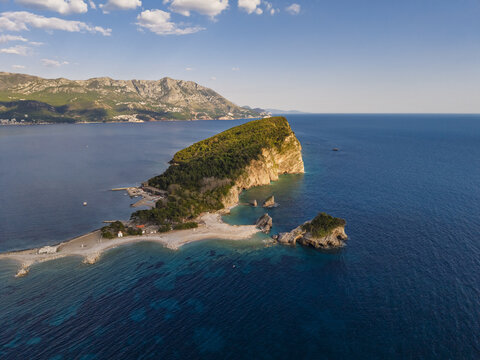 Aerial view of the lush Sveti Nikola Island with rocky cliffs and turquoise waters in the Adriatic Sea, Budva, Budva Municipality, Montenegro.