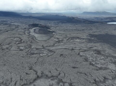 Aerial view of the volcanic Raudaskal crater surrounded by vast, rugged lava fields and dramatic basaltic terrain under a cloudy sky in Akureyri, Rangarthing ytra, Iceland.