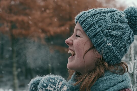 Joyful young woman exhaling visible breath in a snowy forest for winter lifestyle and cold weather apparel advertising