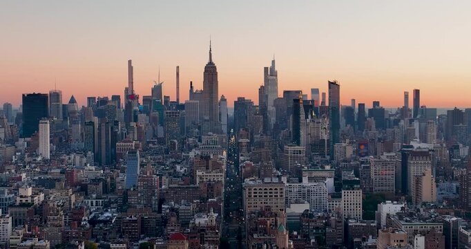 Aerial view of Manhattan skyline with iconic skyscrapers glowing under the warm light of a sunset over the dense urban landscape New York, New York, United States.