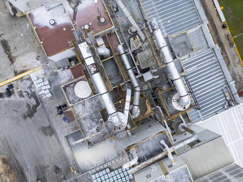 Aerial view of an industrial facility roof featuring metallic ventilation pipes, cooling systems, and flat rooftops in Merida, Yucatan, Mexico.