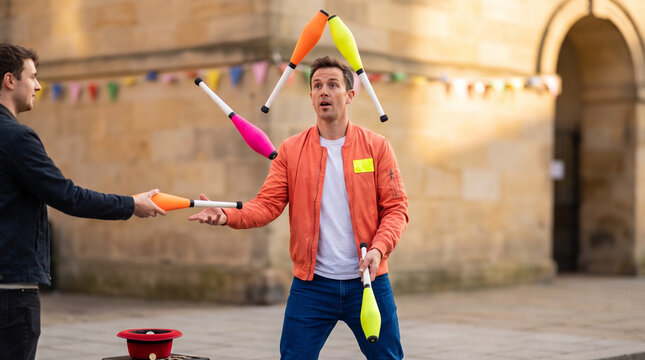 Street performer juggling colorful clubs while entertaining audience outdoors  