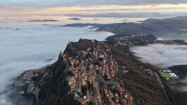 Aerial view of the historic city of San Marino perched on Mount Titano above a sea of clouds during golden hour in San Marino, San Marino, San Marino.