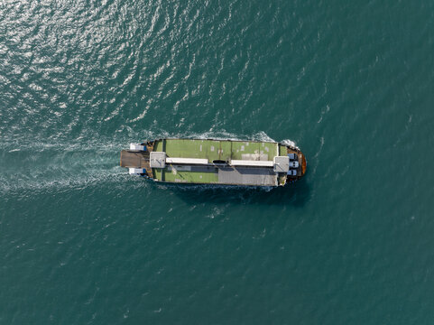 Aerial view of the Koh Chang Ferry crossing the turquoise waters of the Gulf of Thailand with a visible wake trailing behind in Khlong Yai, Trat, Thailand.