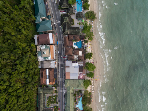 Aerial view of Ko Chang with resorts, swimming pools, a coastal road, and lush forest bordering the sandy beach and turquoise sea in Ko Chang, Trat, Thailand.