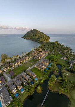 Aerial view of Little Sunshine Resort with private villas, swimming pools, lush gardens, and palm trees situated along the coastline near a tropical island in Klong son, Chang Wat Trat, Thailand.