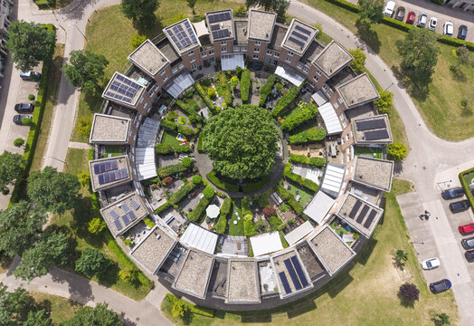 Aerial view of the circular residential housing development featuring private gardens, a large central tree, and solar panels on rooftops in Houten, Utrecht, Netherlands.