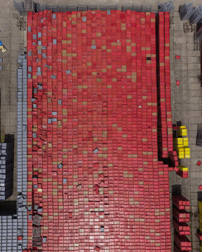 Aerial view of a large outdoor storage area filled with stacks of red plastic crates arranged in rows on a concrete surface, with yellow and grey crates at the edges in Houten, Utrecht, Netherlands.