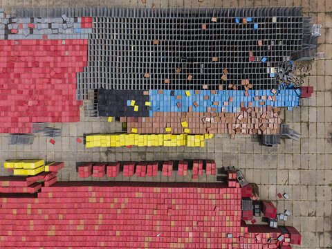 Aerial view of the Oud-Wulven site featuring organized stacks of colorful plastic crates in red, yellow, blue, and grey on a paved industrial yard in Houten, Utrecht, Netherlands.