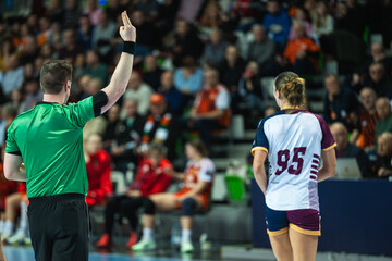 Fototapeta premium A handball referee showing a two-minute suspension sign with fingers during a high-stakes professional sports game.