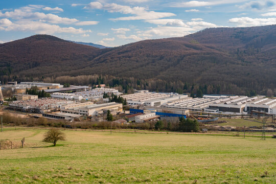 Aerial view of PPS Group industrial complex with large factory buildings and warehouses nestled in a valley surrounded by forested hills in Viglas, Banskobystricky kraj, Slovakia.