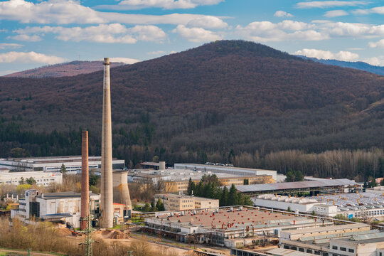 Aerial view of the PPS GROUP a.s. industrial facility with tall chimneys and factory buildings nestled against forested hills in Viglas, Banskobystricky kraj, Slovakia.