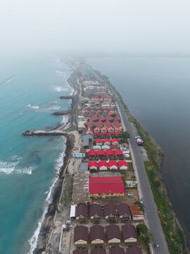 Aerial view of the narrow coastal strip in Pomorie featuring rows of small houses with red roofs situated between the Black Sea and the salt lake, Pomorie, Burgas, Bulgaria.