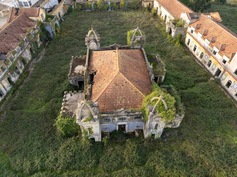 Aerial view of the abandoned Quinta Conde de Sucena estate with overgrown vegetation, weathered terracotta tiled roofs, and surrounding historic structures in Borralha, Aveiro, Portugal.