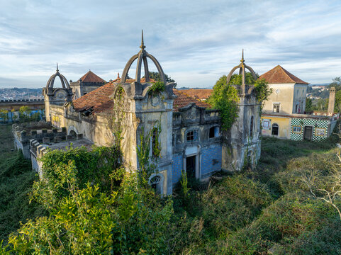 Aerial view of the abandoned Quinta Conde de Sucena mansion with its distinctive domes, weathered tiled walls, and overgrown vegetation in Borralha, Aveiro, Portugal.