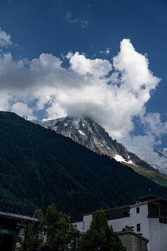 View of Mont Blanc with its snow-capped peak partially obscured by clouds above the town of Chamonix, Auvergne-Rhone-Alpes, France.