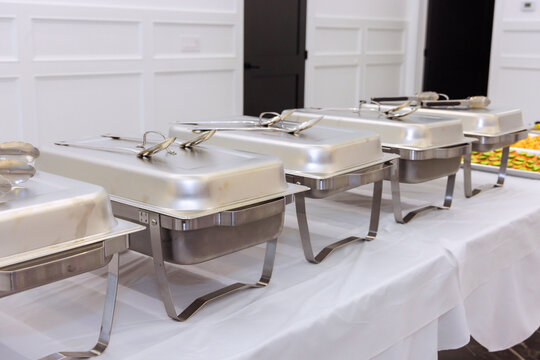 Food trays are arranged neatly on tables at an indoor event, prepared for guests to enjoy their meals.