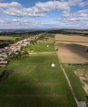 Aerial view of the historic Tesi Windmills and Smithy surrounded by green fields, rural landscape, and the village of Tes, Hungary.