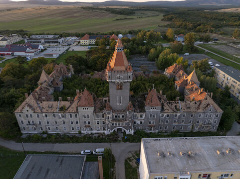 Aerial view of the historic Hajmasker Barracks featuring a prominent central tower, weathered red-tiled roofs, and overgrown courtyards in Hajmasker, Hungary.