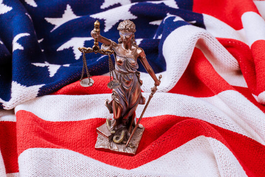 Lady Justice statue holds scales sword while placed on an American flag clear message about justice.