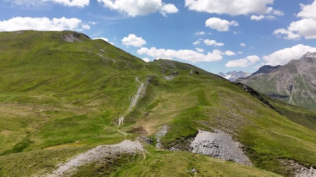 Cinematic aerial drone shot flying over lush green alpine meadows, mountain trails, and a small water reservoir in Obernberg am Brenner, Austria.⁠
