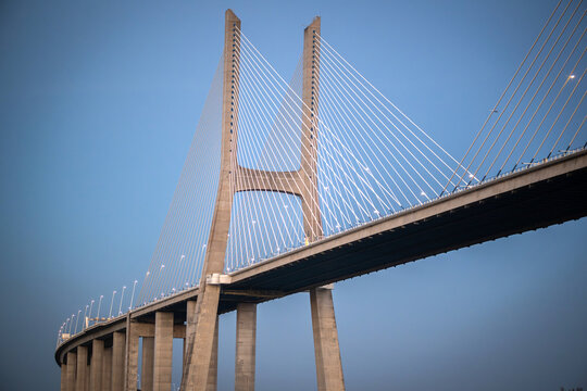 View of the Vasco da Gama Bridge with its tall concrete pylons and cable-stayed design against a clear blue sky in Lisboa, Portugal.