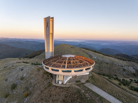 Aerial view of the Buzludzha Monument, a brutalist structure on a mountain peak at sunset, Stara Zagora, Bulgaria.