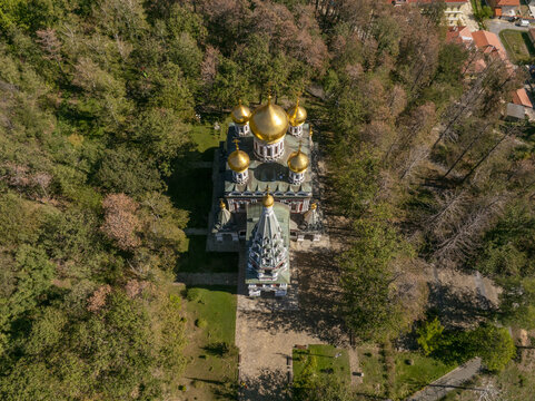 Aerial view of Shipka Memorial Church with its distinctive golden domes surrounded by lush forest in Shipka, Stara Zagora, Bulgaria.