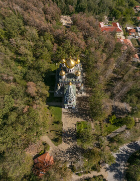 Aerial view of the Shipka Memorial Church with its golden domes nestled among the dense autumn forest in Shipka, Stara Zagora, Bulgaria.