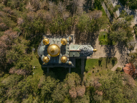 Aerial view of Shipka Memorial Church with its distinctive golden domes surrounded by lush green trees and forest in Shipka, Stara Zagora, Bulgaria.