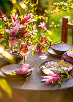 Table setting in garden on sunset light. Table decorated with magnolia flowers under magnolia tree.