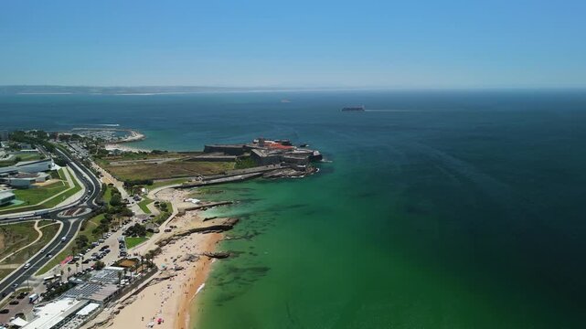Aerial view of the historic Forte de Sao Juliao da Barra situated on the coastline with sandy beach and clear blue sea in Portugal.