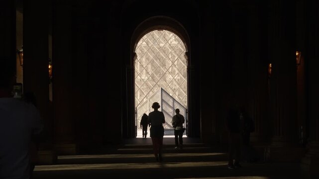Lone figure walking toward the glass pyramid in Paris