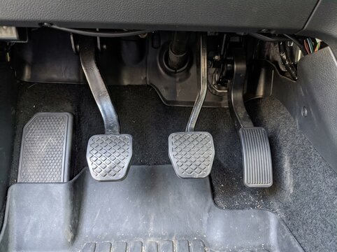 Close up view of the three metal car pedals inside a manual transmission vehicle showing the clutch brake and accelerator pedal for the driver